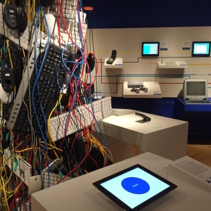 Tower of keyboards and wires in the center of the fourth-floor gallery; Newton visible against the history wall